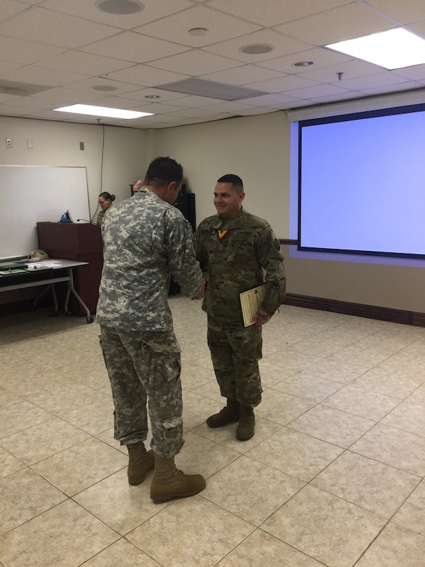 Staff Sgt. Omar Rodriguez is presented with the military order of Saint Christopher by Command Sgt. Maj. Rene Berlingeri, an Ancient Order of Saint Christopher recipient, during a ceremony on Fort Buchanan, October 23.