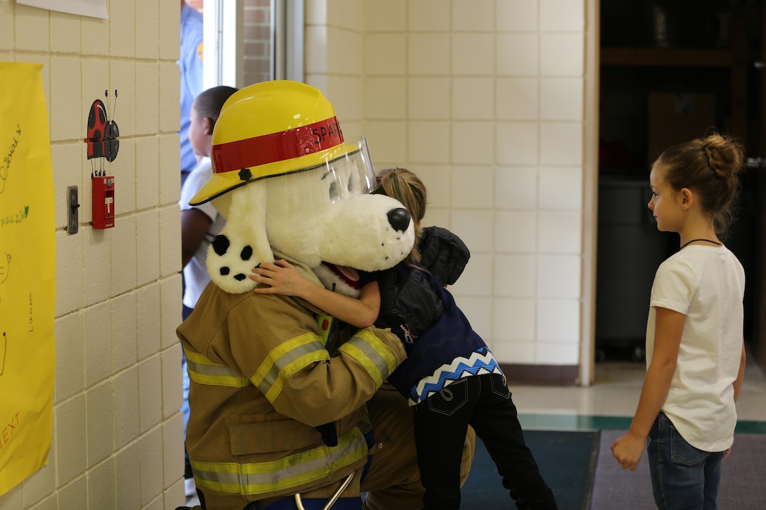 Sparky the Fire Dog hugs a student at W.J. Gurganus Elementary School in Havelock, N.C., Oct. 20, 2016. The Cherry Point Fire and Emergency Services Department visited the school to demonstrate what to do in fire emergencies and how to prevent them. The students also learned about the equipment firefighters use every day to complete their mission. Sparky is the mascot for the Cherry Point Fire and Emergency Services Department. (U.S. Marine Corps photo by Lance Cpl. Mackenzie Gibson/Released)