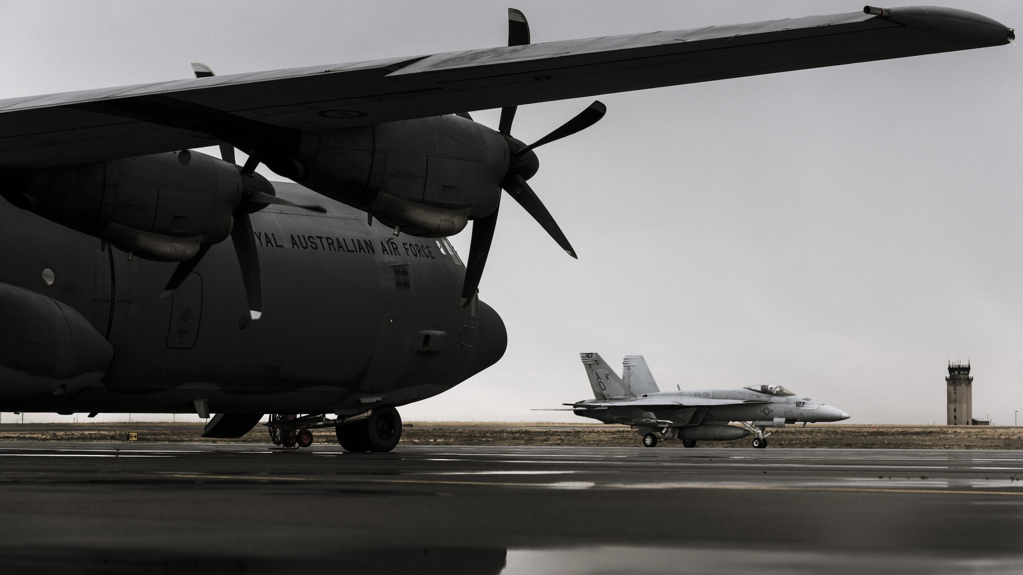 A Navy F-18 from Naval Air Station Oceana, Virginia, passes under the wings of a Royal Australian Air Force C-130J at Mountain  Home Air Force Base, Idaho, Oct. 23, 2016. Units from across the world visit the base to use its extensive training ranges. (U.S. Air Force photo by Senior Airman Connor J. Marth/Released)