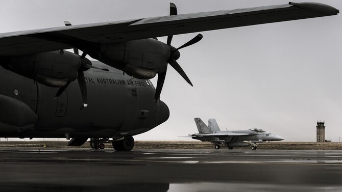 A Navy F-18 from Naval Air Station Oceana, Virginia, passes under the wings of a Royal Australian Air Force C-130J at Mountain  Home Air Force Base, Idaho, Oct. 23, 2016. Units from across the world visit the base to use its extensive training ranges. (U.S. Air Force photo by Senior Airman Connor J. Marth/Released)