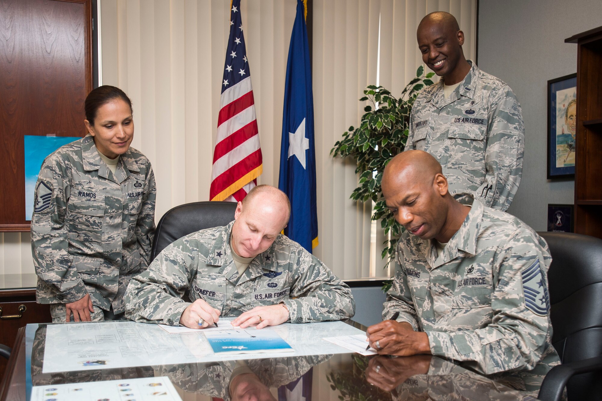 From left: Master Sgt. Elizabeth Ramos, 412th Force Support Squadron, watches as Brig. Gen. Carl Schaefer, 412th Test Wing commander, and Chief Master Sgt. Todd Simmons, 412th TW command chief, fill out their Combined Federal Campaign donation forms at wing headquarters Oct. 24. Ramos and 1st Lt. Christophe Bangerezako, 412th Medical Support Squadron, are this year’s points of contact. (U.S. Air Force photo by Ethan Wagner)