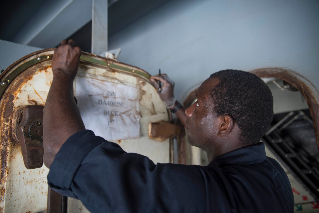 Navy Petty Officer 3rd Class Landing Coly replaces the gutter of the door to a boat davit aboard the aircraft carrier USS Dwight D. Eisenhower in the Persian Gulf, Oct. 25, 2016. Navy photo by Seaman Joshua Murray