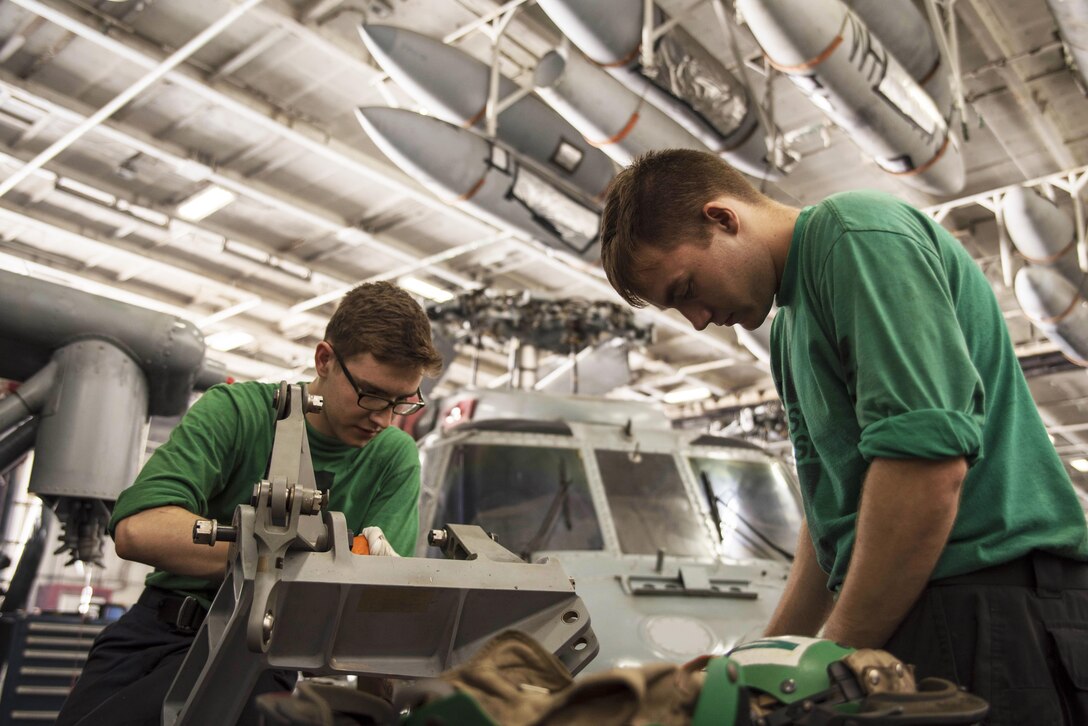 Navy Seaman Shannon Potter, left, and Petty Officer 3rd Class Ethan Nelson clean aircraft components in the hangar bay of the aircraft carrier USS Dwight D. Eisenhower in the Persian Gulf, Oct. 25, 2016. Potter and Nelson are aviation structural mechanics. Navy photo by Seaman Joshua Murray
