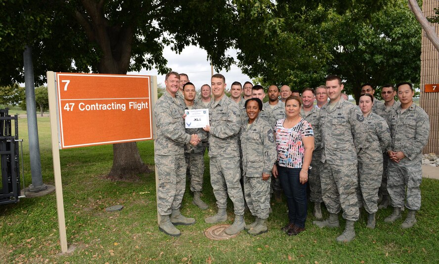 Airman 1st Class Garret Parker, 47th Contracting Squadron contract specialist (front center), accepts the “XLer of the Week” award from Col. Thomas Shank (front left), 47th Flying Training Wing commander, and Chief Master Sgt. Erica Shipp (front right), 47th Mission Support Group superintendent on Laughlin Air Force Base, Texas, October 18, 2016. The XLer is a weekly award chosen by wing leadership and is presented to those who consistently make outstanding contributions to their unit and Laughlin. (U.S. Air Force photo/Airman 1st Class Benjamin N. Valmoja)