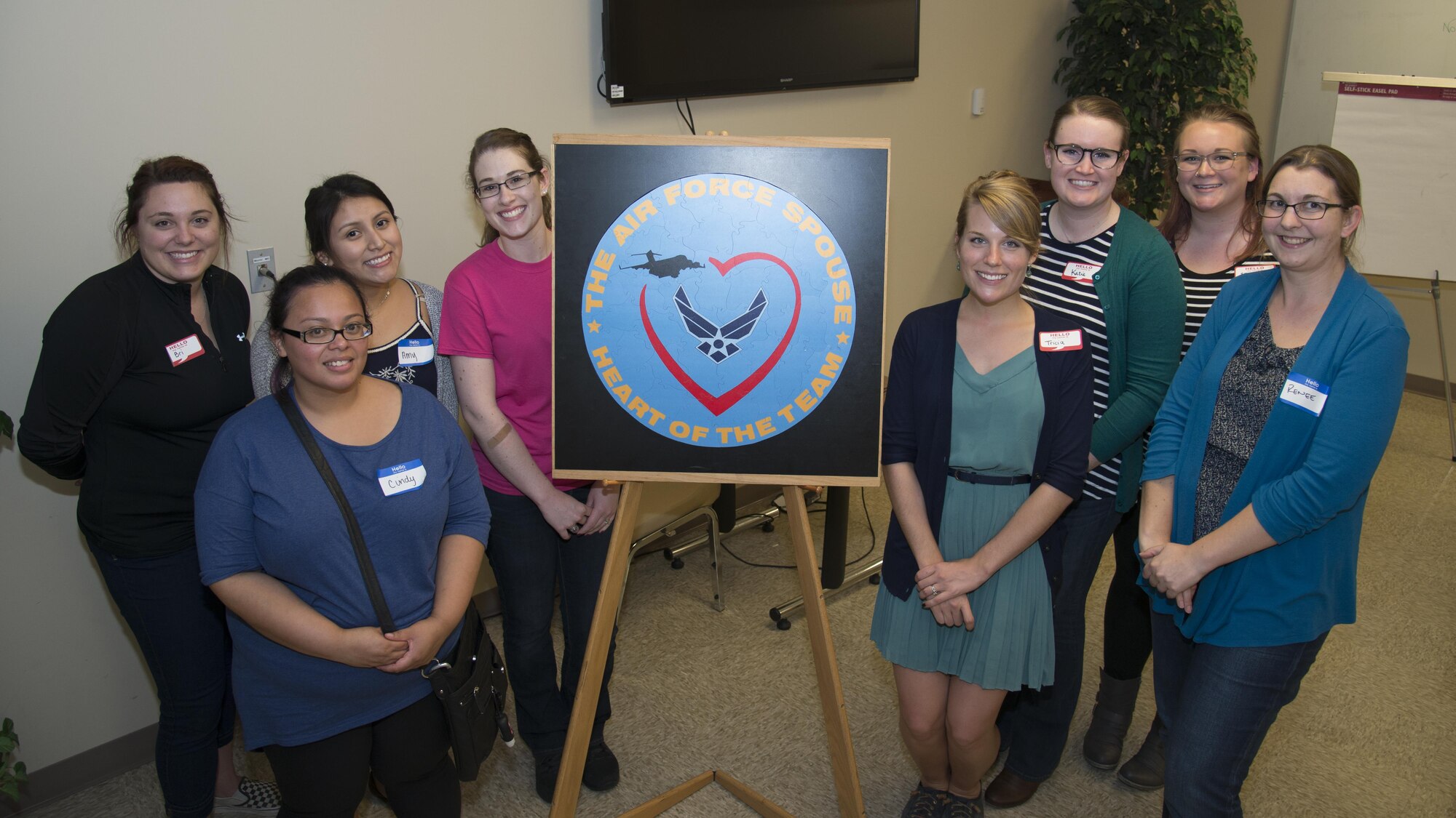 Military spouses stand beside the Heartlink Spouse Orientation Program puzzle Oct. 19, 2016, at Chapel 1 on Dover Air Force Base, Del. Heartlink is an Air Force program designed to help spouses acclimate by introducing them to helping agencies on base. (U.S. Air Force photo by Staff Sgt. Jared Duhon) 