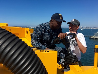 160915-N-IL267-007 SAN DIEGO (Sept. 15, 2016) Tracy Harasti, an environmental protection specialist with Naval Surface Warfare Center, Carderock Division, trains Seaman Uzoma Hojo in the use of the Mobile Cleaning Reclaim and Recovery System on the flight deck of the amphibious assault ship USS America (LHA 6). (U.S. Navy photo by Dustin Q. Diaz/Released)