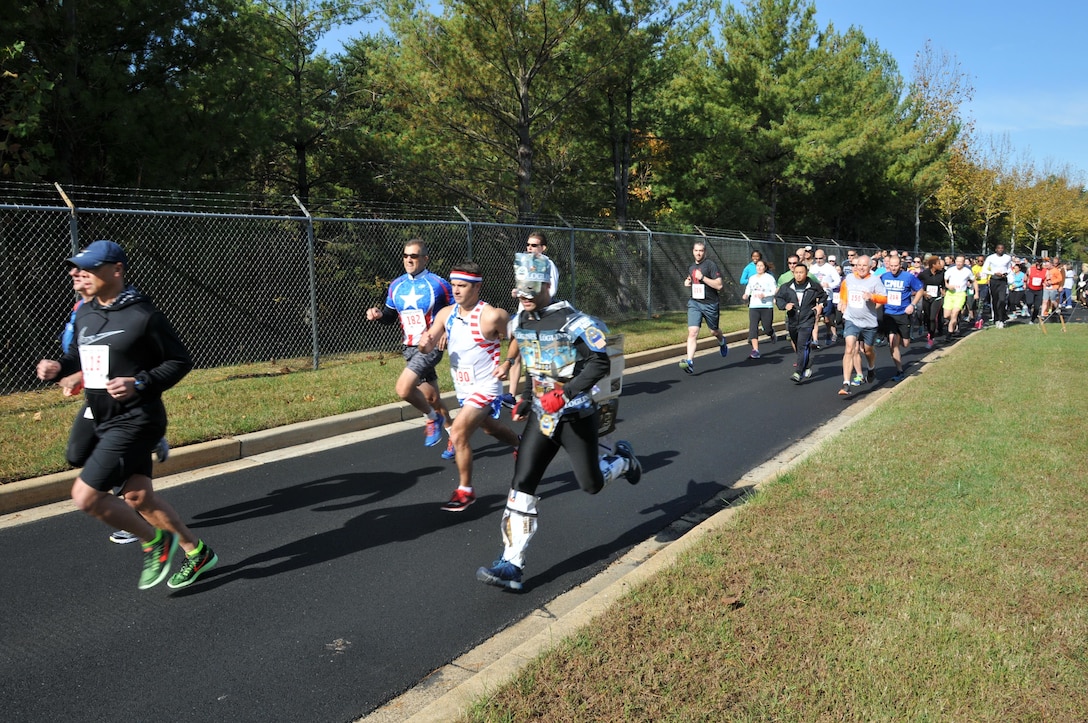 At the 2016 Monster Dash, runners including DLA's 'LogLinus' (foreground, in costume) and DTRA's Adam Letizio, who finished second for men (center, in red/white/blue) start their way on the course.