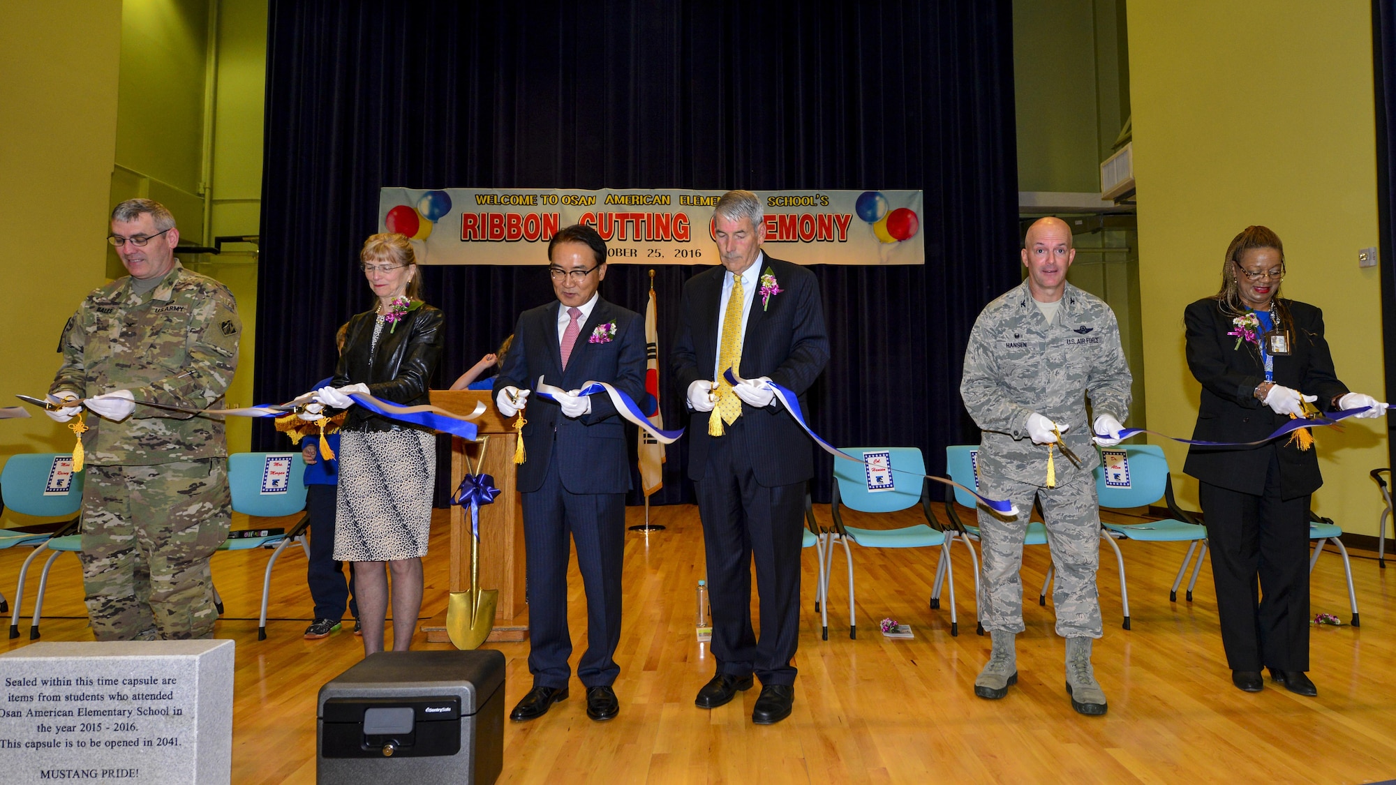 Key members of Team Osan, Department of Defense Education Activity and the local area cut a ribbon symbolizing the opening of the new Osan American Elementary School at Osan Air Base, Republic of Korea, Oct. 25, 2016. The ribbon cutting ceremony also included the students dedicating a time capsule, which will be buried in front of the new school until 2041. (U.S. Air Force photo by Senior Airman Victor J. Caputo)