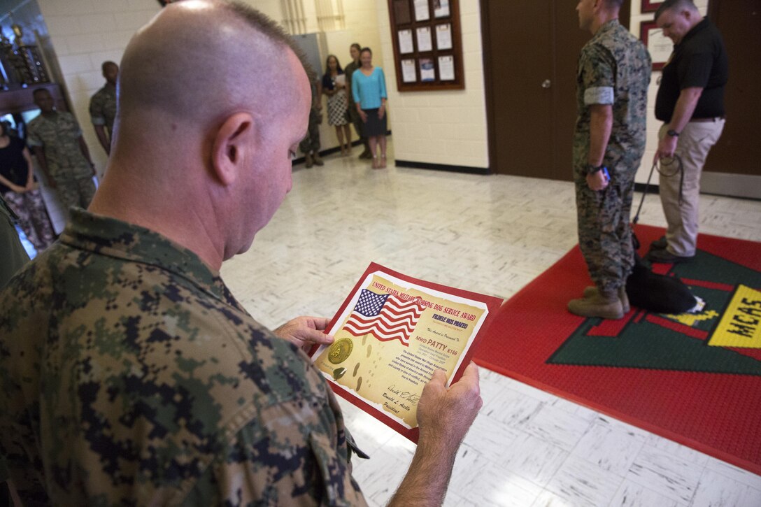 Lt. Col. Robert T. Sweginnis reads a citation honoring retired military working dog, Patti during an award ceremony Oct. 24 on Marine Corps Air Station Futenma, Okinawa, Japan. The award ceremony honored Patti, who served as a combat tracking dog during Operation Iraqi Freedom in 2007. Patti served alongside her handler, James Altman, who was a staff sergeant at the time, and was injured in the line of duty. Her injuries left her paralyzed and the two worked together through her six-month rehabilitation period and have been inseparable ever since. Altman permanently adopted Patti in 2008, continuing their partnership even after the mission was complete. Patti received a medal and a citation from the U.S. War Dogs Association, stating, “The United States War Dogs Association presents this award to military canines who have served in the Armed Forces of the United States of America with honor, courage and loyalty in time of conflict, so that we may live in freedom.”