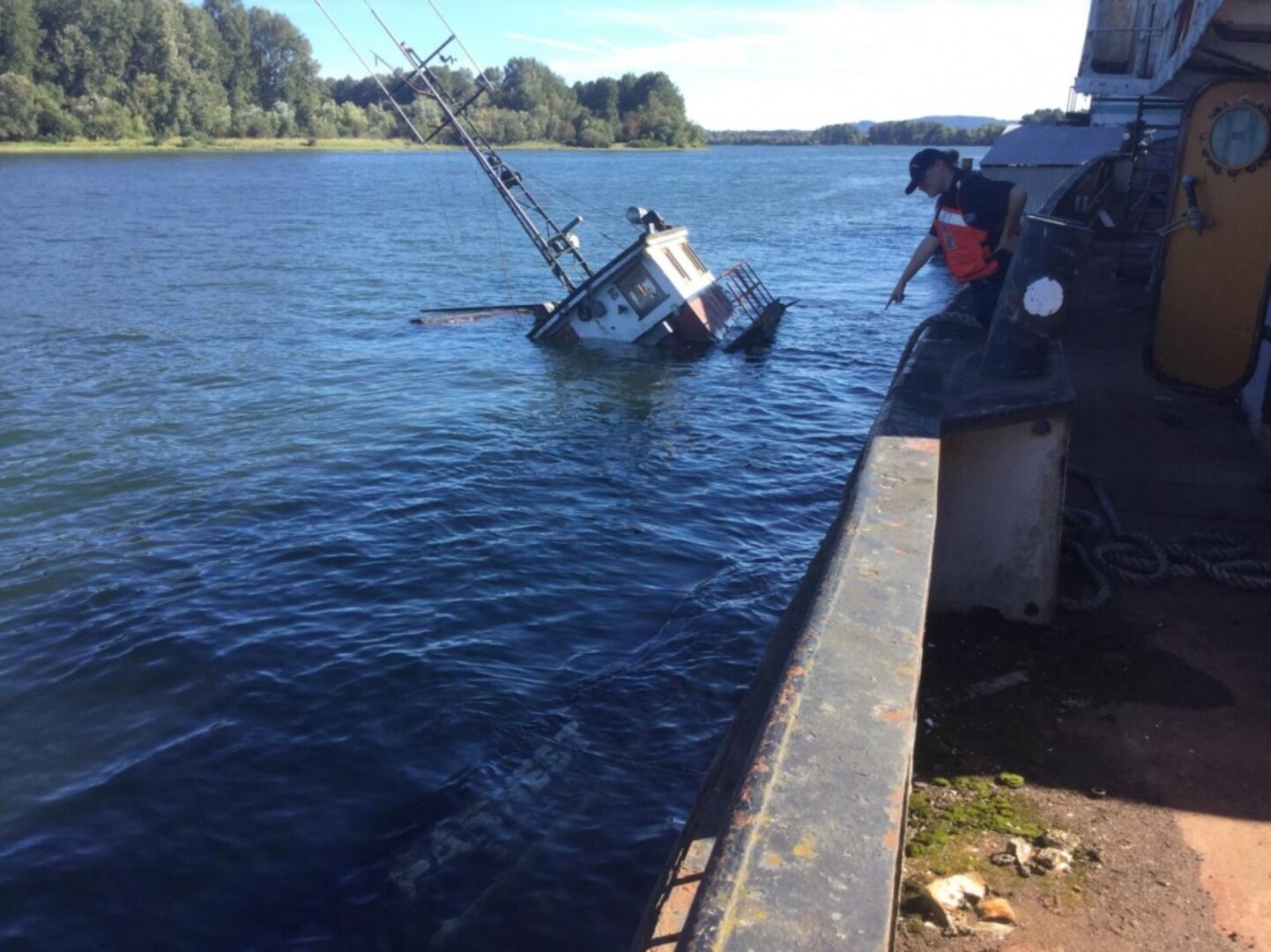 The Coast Guard Responds to a sunken tugboat.  A Marine Science Technician from Incident Management Division Detachment Portland, points to a sunken motor vessel, which sank in the Columbia River near Goble, Oregon. Personnel from the Coast Guard and several Oregon State agencies are partnering in response to the sinking. (U.S Coast Guard photo by Petty Officer 2nd Class Alisha Carr)