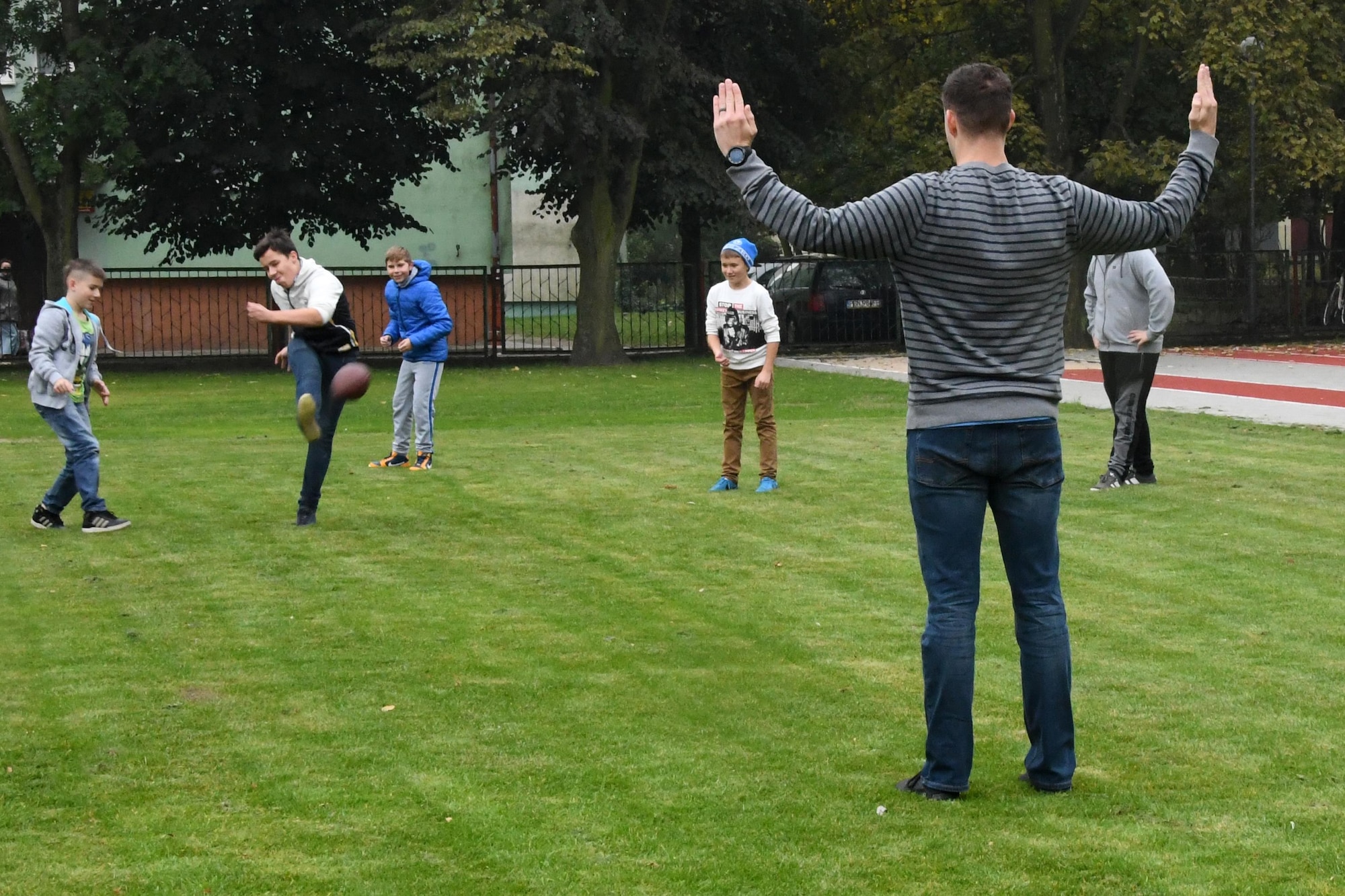 Capt. Chris Freed, 37th Airlift Squadron pilot, holds his arms up forming an upright while playing football with students at Elementary School No. Nine in Gniezno, Poland, Oct. 18, 2016. Freed made a cultural orientation visit to the school while the 94th Airlift Wing, Dobbins Air Reserve Base, Georgia, and the 86th Airlift Wing, Ramstein Air Base, Germany, are working with the Polish air force during Aviation Detachment 17-1 in support of Operation Atlantic Resolve. (U.S. Air Force photo by Staff Sgt. Alan Abernethy)