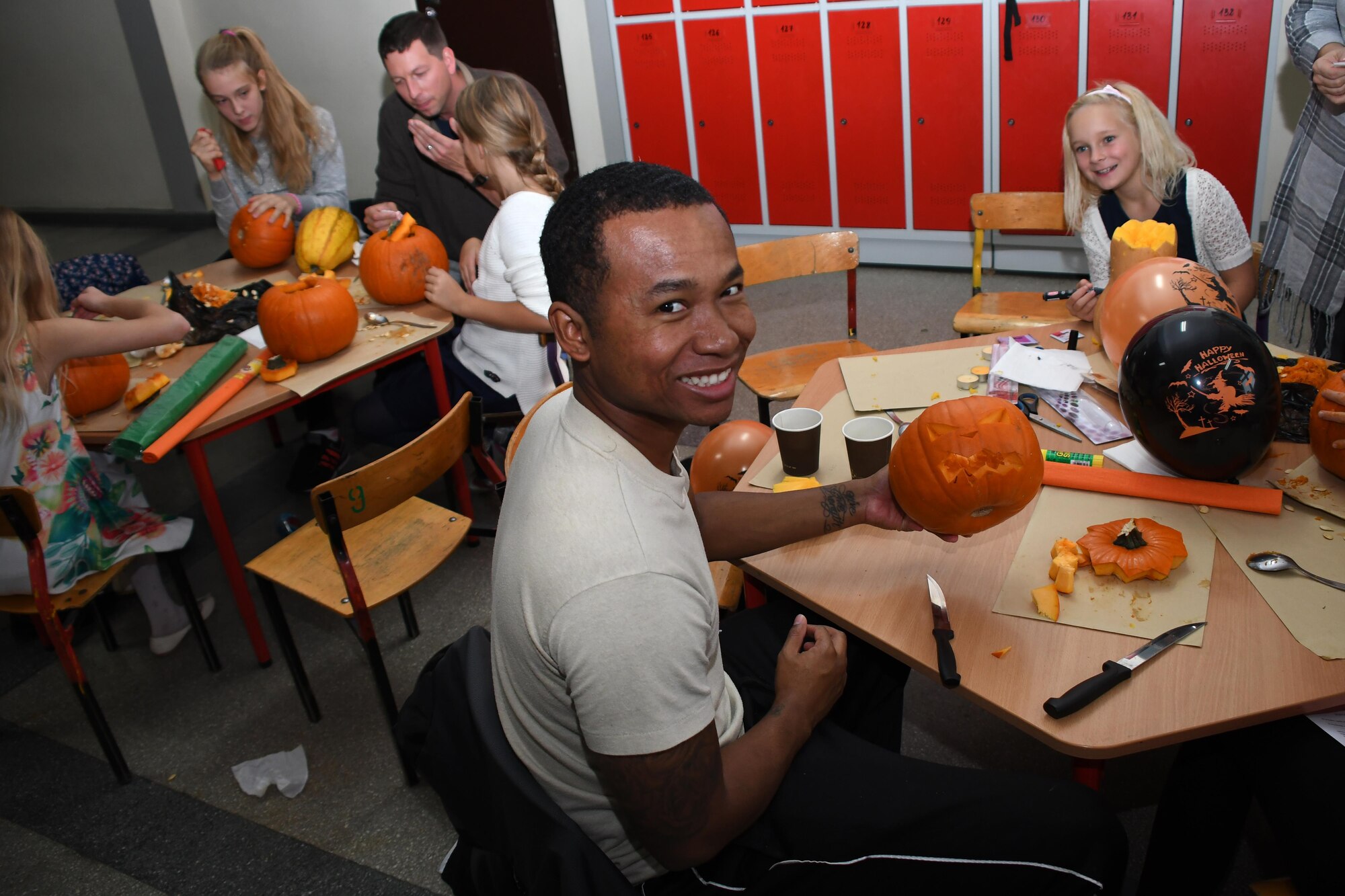 Senior Airman Arsenio Small, 86th Airlift Wing flight service center journeyman, and Staff Sgt. Michael Sterchi, 700th Airlift Squadron loadmaster, carve pumpkins with students at Elementary School No. Nine in Gniezno, Poland, Oct. 19, 2016. Pumpkin carving was one of several activities the Airmen participated in during a cultural orientation visit to the school while working with the Polish air force during Aviation Detachment 17-1 in support of Operation Atlantic Resolve. (U.S. Air Force photo by Staff Sgt. Alan Abernethy)