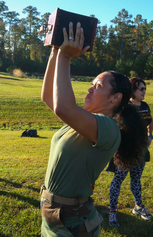 Tatianna K. Wade, military spouse, takes part in the ammo can lifts that are a part of the combat fitness test given to all Marines with other spouses during J. Wayne Day at Camp Johnson on Marine Corps Installation Camp Lejeune Oct. 21.  J. Wayne Day is a day where military spouses participate in activities representing what their Marines take part in on a constant basis.