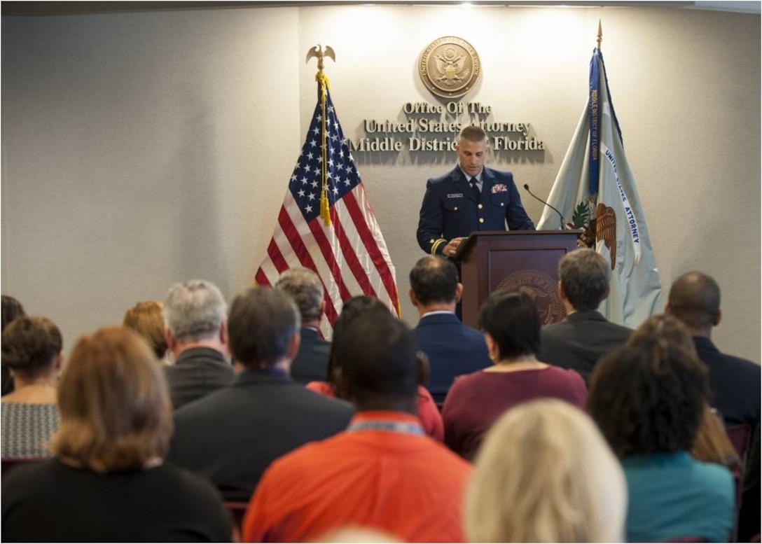 A Coast Guard public affairs officer, speaks to an audience during a ceremony at U.S. Attorney's Office Middle District of Florida where an interagency team received the Coast Guard Distinguished Public Service Award for their efforts to combat transnational criminal organizations involved in drug trafficking. (U.S. Coast Guard Photo by Petty Officer 1st Class Michael De Nyse)