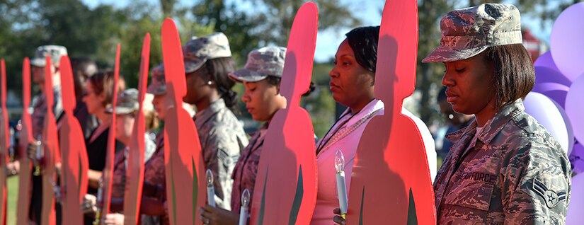 Members of the 628th Medical Group hold up red silhouettes during a candlelit vigil to raise awareness for domestic abuse victims and honor military families affected by abuse at the Hunt Community Center here, Oct. 24, 2016. Red silhouettes are used across the United States to recognize victims who lost their lives to domestic violence.