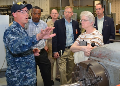 Chief Petty Officer Jason Broenneke explains how Sailors at Southeast Regional Maintenance Center (SERMC) use a metal lathe to create replacement parts for ship repairs to (from L to R) Lt. Col. Al Warthen, USMC, CAPT Dave Gombas, Mr. Craig Collier, Ms. Vickie Plunkett and Mr. Andrew Warren who are professional staff members on the House Armed Services Committee. The delegation was on Mayport to engage key staff on ship maintenance and workload. (Photo by Scott Curtis)