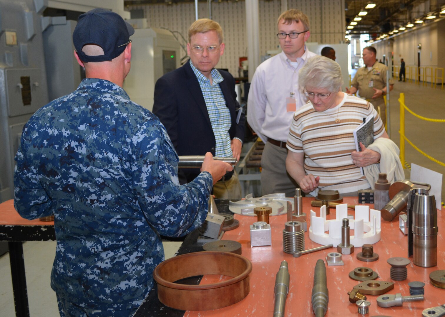 Chief Petty Officer Jason Broenneke shows examples of fabricated shipboard materiel created by Sailors at Southeast Regional Maintenance Center (SERMC) to (from L to R) Mr. Craig Collier and Ms. Vickie Plunkett who are professional staff members on the House Armed Services Committee. The staffers left with a better understanding regarding the different production lines, shops and labs present at SERMC. (Photo by Scott Curtis)