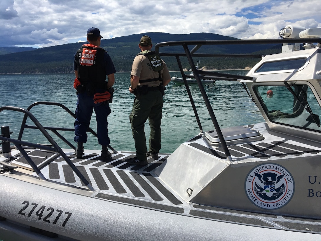 A Coast Guardsman surveys the waters alongside a U.S. Customs and Border Protection agent while conducting border patrol and law enforcement operations on Lake Koocanusa in Montana. This cooperative mission helps build better partnerships and training between the two agencies. (U.S. Coast Guard photo by Chief Warrant Officer Brian Hennessy)