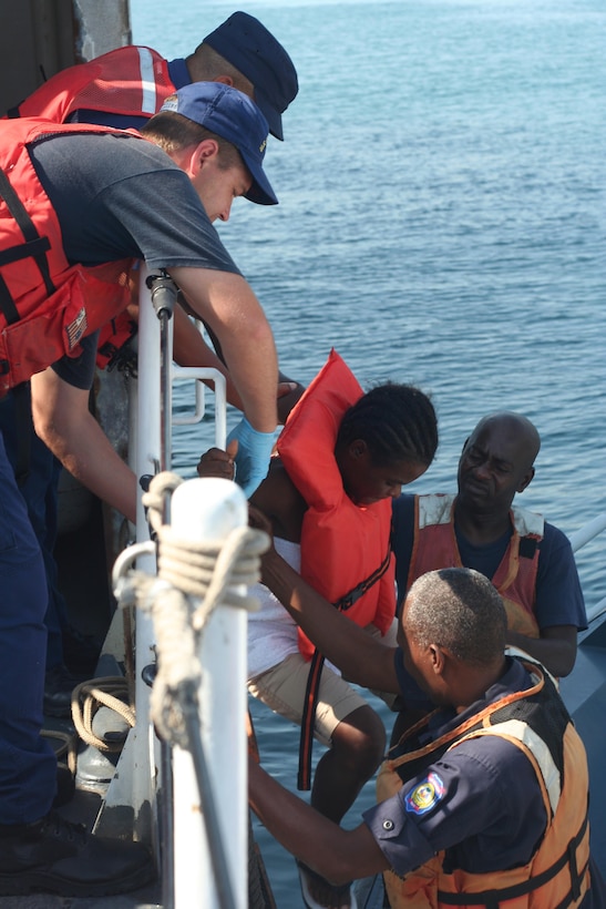 A boatswain’s mate aboard the Coast Guard Cutter Tahoma, helps a Haitian migrant down to a small boat before being repatriated to Haiti. The crew of the Tahoma received the 88 Haitian nationals from the crew of the CGC Hamilton after they were rescued from a 50-foot sail freighter that was taking on water 45 miles north of Isle de Tortue, Haiti. U.S. Coast Guard photo by Petty Officer 3rd Class Bryan Bumstead. (U.S. Coast Guard photo by Petty Officer 3rd Class Bryan Bumstead)