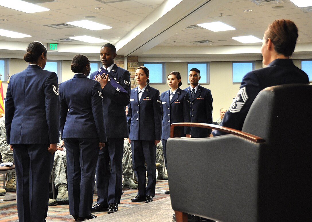 Airmen and NCOs from the Air Reserve Personnel Center participate in a passing of the flag to commemorate the ranks held by Chief Master Sgt. Ruthe Flores, Air Reserve Personnel Center command chief, during Flores' retirement ceremony at Buckley Air Force Base, Colo., Oct. 27. Members of ARPC joined Flores’ friends, family and colleagues to celebrate the chief’s 28 years of service to the Air Force. (U.S. Air Force photo by Tech. Sgt. Beth Anschutz)