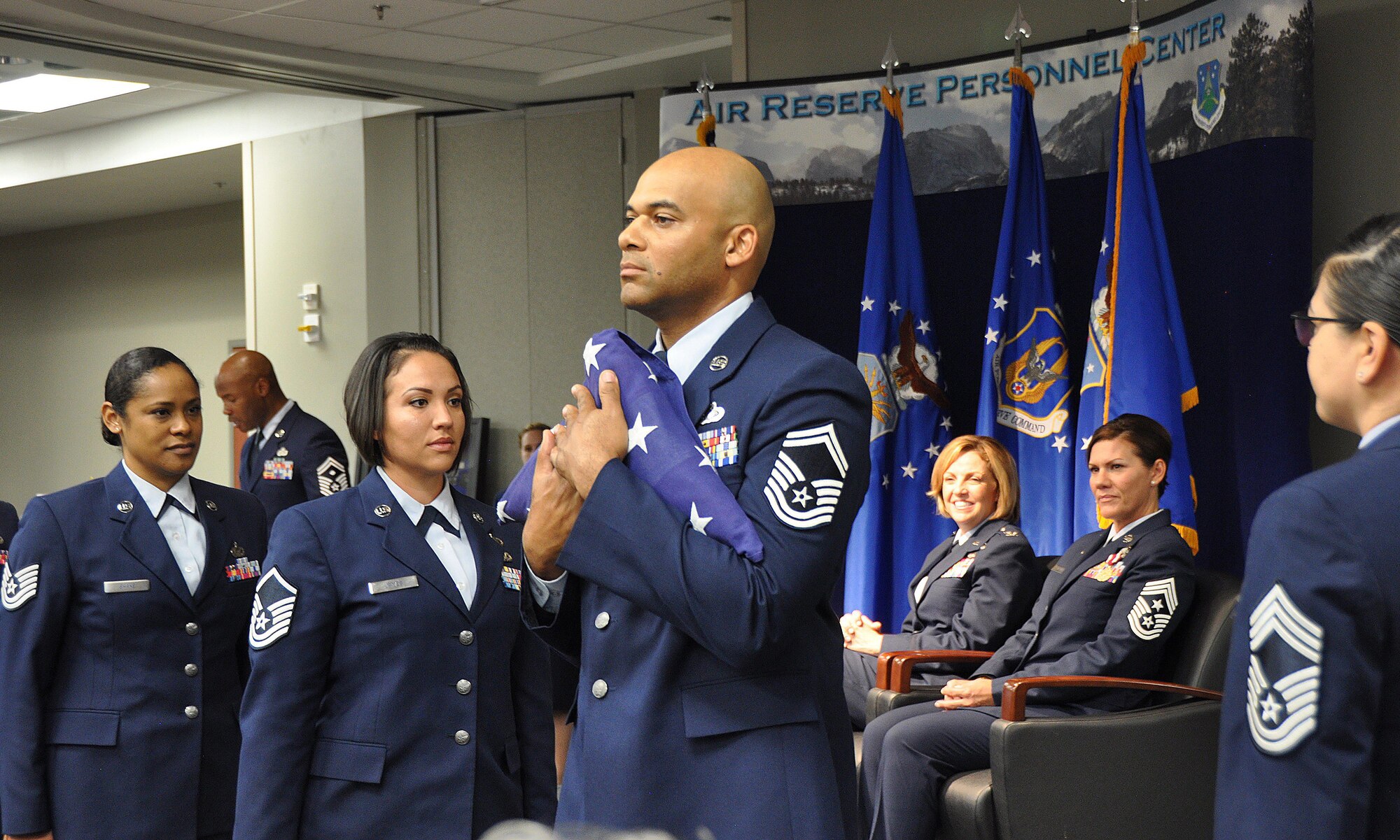 Senior Master Sgt. David Smashum (center), Master Sgt. Jessica James (left center), and Technical Sgt. Taryn Shake (far left), all from the Air Reserve Personnel Center, participate in the passing of the flag to commemorate each rank held by Chief Master Sgt. Ruthe Flores, ARPC command chief, during Flores' retirement ceremony at Buckley Air Force Base, Colo., Oct. 27. Members of ARPC joined Flores’ friends, family and colleagues to celebrate the chief’s 28 years of service to the Air Force. (U.S. Air Force photo by Tech. Sgt. Beth Anschutz)