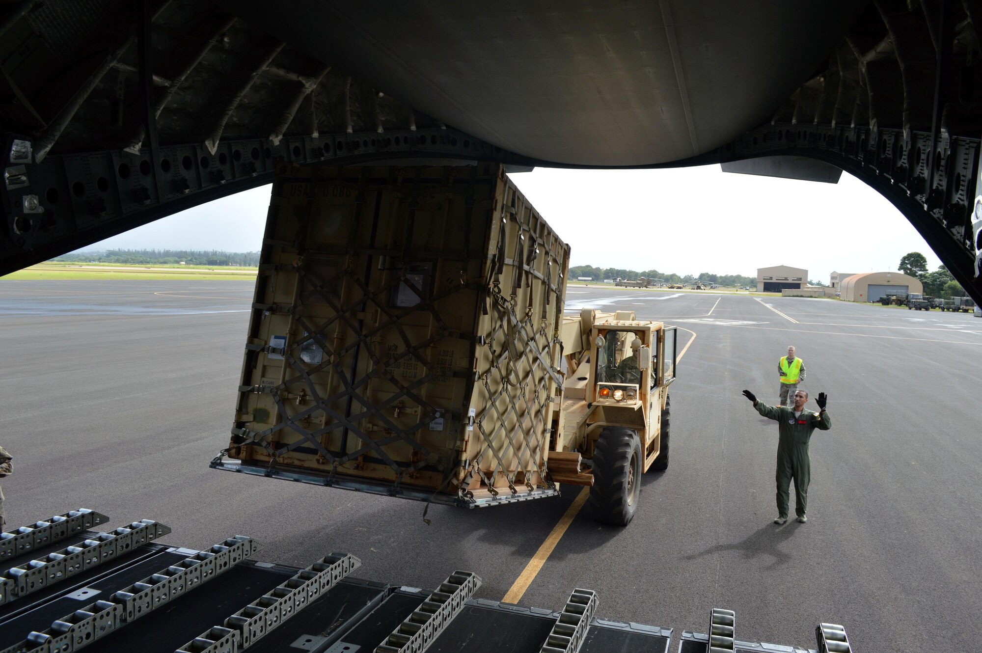 U.S. Air Force Tech. Sgt. Terry Greenwood (right), a C-17 aircrew member assigned to the 535th Airlift Squadron, 15th Wing, ground guides Army Spc. James Risenhoover, a wheeled vehicle mechanic assigned to 3rd Squadron, 4th Cavalry Regiment, 3rd Brigade Combat Team (BCT), 25th Infantry Division, to ensure a safe pallet load aboard the C-17 at Wheeler Army Airfield, Hawaii, on Oct. 24, 2016.. More than 200 Soldiers and equipment from the 3rd BCT are participating in Lightning Forge 17 at Pohakuloa Training Area on the island of Hawaii. (U.S. Army photo by Staff Sgt. Armando R. Limon)