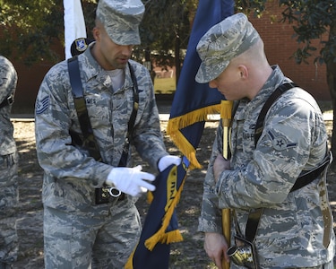 Tech. Sgt. Matthew James, left, Air Force Honor Guard Mobile Team colors element trainer, helps Airman Tucker Armstrong, right, base honor guard member, how to place the slack of the flag behind him here, Oct. 25, 2016. The mobile team is comprised of members from the Air Force Honor Guard training flight. 