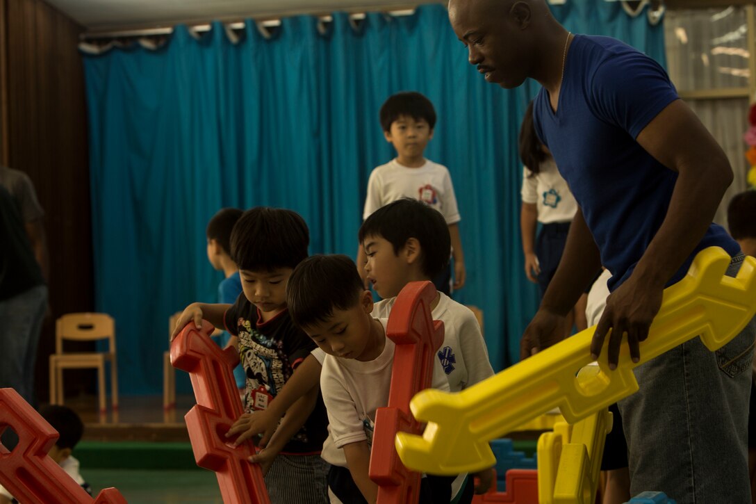 U.S. Marine Corps GySgt. Raetheon W. Mitchell, a motor transportation maintenance chief at Garrison Mobile Equipment, Marine Corps Base Smedley Butler, III Marine Expeditionary Force, helps the children of Chatan-Daini Kindergarten put together a toy house during a visit to an elementary school in Okinawa, Japan,  Oct. 26, 2016. The Marines were able to show the local children the similarities between the U.S. and Japanese cultures through a variety of games and books. (U.S. Marine Corps photo by Lance Cpl. Kelsey Dornfeld)