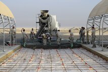 Airmen of the 386th Expeditionary Civil Engineering Squadron lay concrete on the flightline at an undisclosed location in Southwest Asia 24 Oct., 2016. The 386th ECES is expanding sunshades to prepare for an upcoming transition from MQ-1 Predators to MQ-9 Reapers. (U.S. Air Force photo by Capt. Casey Osborne/Released)