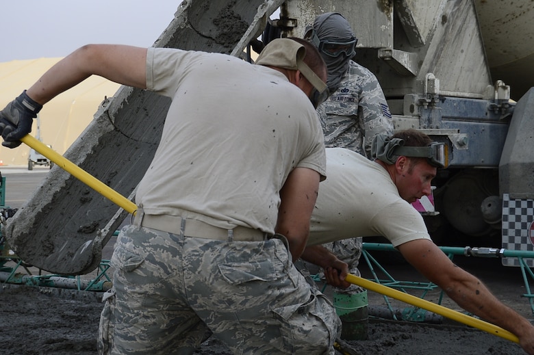 Senior Airman Jon Martinez, 386th Expeditionary Civil Engineering Squadron pavements and equipment apprentice, lays concrete on the flightline at an undisclosed location in Southwest Asia 24 Oct., 2016. The 386th ECES is expanding sunshades to prepare for an upcoming transition from MQ-1 Predators to MQ-9 Reapers. (U.S. Air Force photo by Capt. Casey Osborne/Released)