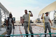 From left, Airman 1st Class Marco Small-Gonzalez, Staff Sgt. Cameron Kruell and Senior Airman Jon Martinez, 386th Expeditionary Civil Engineering Squadron pavements and equipment technicians, review their progress while smoothing out concrete at an undisclosed location in Southwest Asia 24 Oct., 2016. The 386th ECES is expanding sunshades to prepare for an upcoming transition from MQ-1 Predators to MQ-9 Reapers. (U.S. Air Force photo by Capt. Casey Osborne/Released)