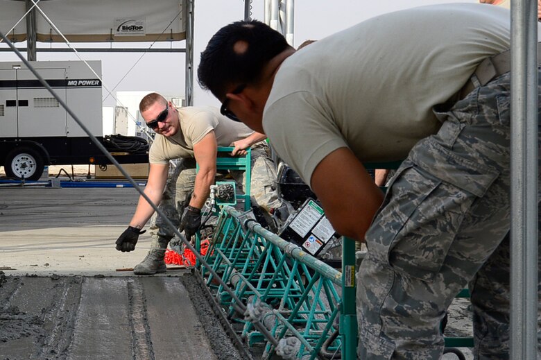 Airman 1st Class Matthew Fleming, left, and Senior Airman Fabion Perez, right, 386th Expeditionary Civil Engineering Squadron pavements and equipment technicians, smooth out concrete at an undisclosed location in Southwest Asia 24 Oct., 2016. The 386th ECES is expanding sunshades to prepare for an upcoming transition from MQ-1 Predators to MQ-9 Reapers. (U.S. Air Force photo by Capt. Casey Osborne/Released)