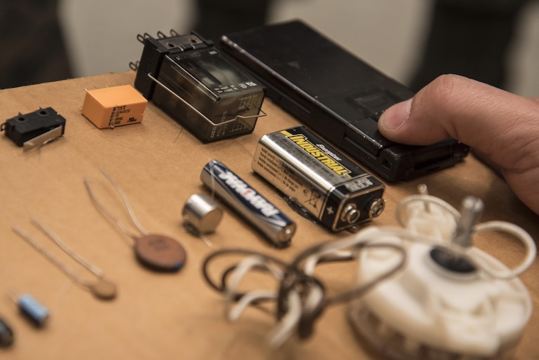 U.S. Air Force Senior Airman Alexander Thompson, an explosive ordnance disposal technician with the 35th Civil Engineer Squadron, shows different types of components used to trigger improvised explosive devices at Misawa Air Base, Japan, Oct. 20, 2016. EOD teams train to recognize items which can be put together to create an IED. During training, personnel use an x-ray device showing suitcase contents and must identify each item and how it can be used in an IED. (U.S. Air Force photo by Airman 1st Class Sadie Colbert)