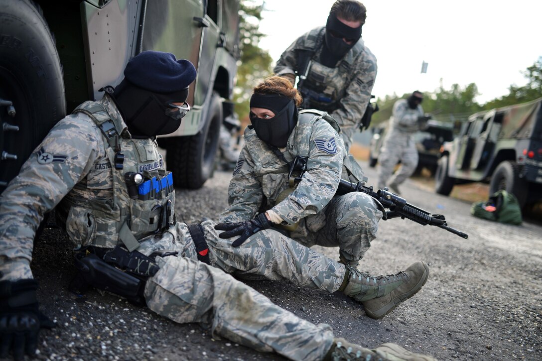 Air Force Tech Sgt. Lisha Terry, right, responds to simulated enemy fire while providing basic first aid to a role-playing casualty during tactical combat casualty care training at Francis S. Gabreski Airport in Westhampton Beach, N.Y., Oct. 21, 2016. Terry is assigned to the 106th Rescue Wing Security Forces Squadron. Air National Guard photo by Staff Sgt. Christopher S. Muncy