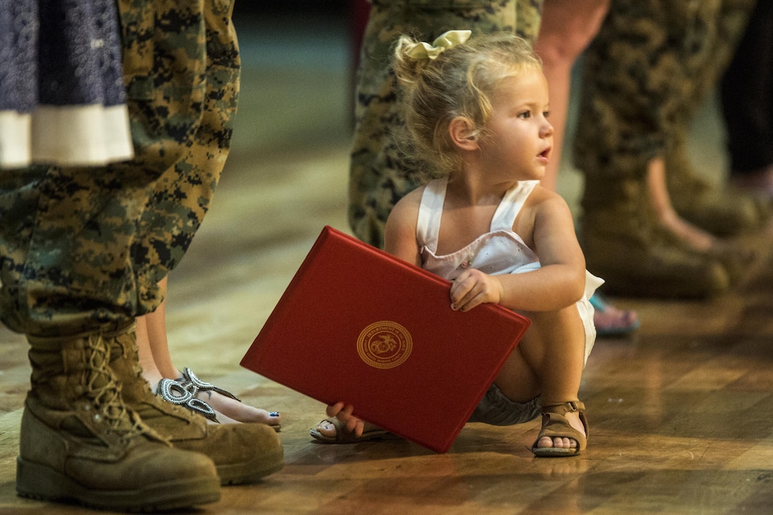 A Marine’s daughter holds his re-enlistment certificate during a formation at Camp Foster in Okinawa, Japan, Oct. 27, 2016. Many families came to support the Marines. Marine Corps photo by Sgt. Isaac Ibarra