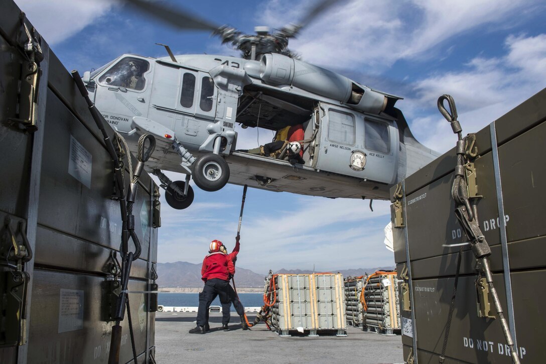 Navy Petty Officer 1st Class Blake Harrington spots Seaman Xavier Williams as he loads a pallet of ammunition onto an MH-60S Seahawk on the flight deck of the USS Boxer during an ammunition offload in the Pacific Ocean, Oct. 26, 2016. The amphibious assault ship is conducting routine operations off the coast of Southern California. The Seahawk is assigned to Helicopter Sea Combat Squadron. Navy photo by Petty Officer 3rd Class Jesse Monford