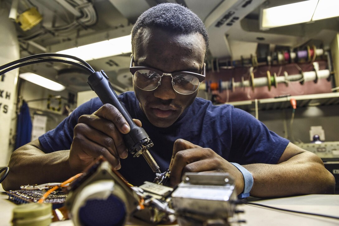 Navy Petty Officer 2nd Class Daniel Maynard desolders a flex print assembly in the avionics shop of the aircraft carrier USS Dwight D. Eisenhower in the Persian Gulf, Oct. 23, 2016. Maynard, an aviation electronics technician, helps inspect, repair and maintain aircraft avionics. The Eisenhower is supporting Operation Inherent Resolve, maritime security operations and theater security cooperation efforts in the U.S. 5th Fleet area of operations. Navy photo by Seaman Christopher A. Michaels
