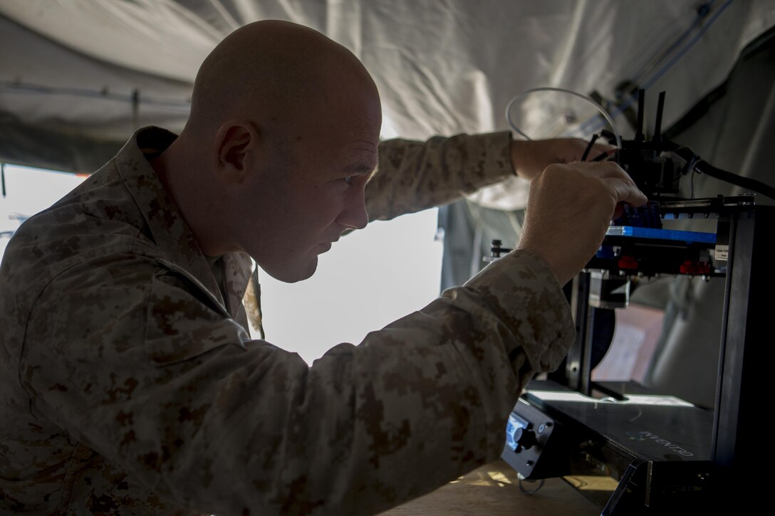 U.S. Marine Corps Chief Warrant Officer 2 Mathew Wright, a motor transportation maintenance officer with Marine Wing Support Squadron 372 conducts maintenance on an Invent3D printer during a 3D printer integration exercise at site 50 training area, Wellton, Ariz., Oct. 18, 2016. Wright used the additive manufacturing (AM) equipment to make objects from 3d model data throughout Weapons Tactics Instructors (WTI) course 1-17.  Marine Aviation Weapons and Tactics Squadron One (MAWTS-1) cadre host WTI which emphasizes operational integration of the six functions of Marine Corps aviation in support of a Marine Air Ground Task Force. MAWTS-1 provides standardized advanced tactical training and certification of unit instructor qualifications to support Marine aviation Training and Readiness and assists in developing and employing aviation weapons and tactics. (U.S. Marine Corps photo by Lance Cpl. Andrew Huff)