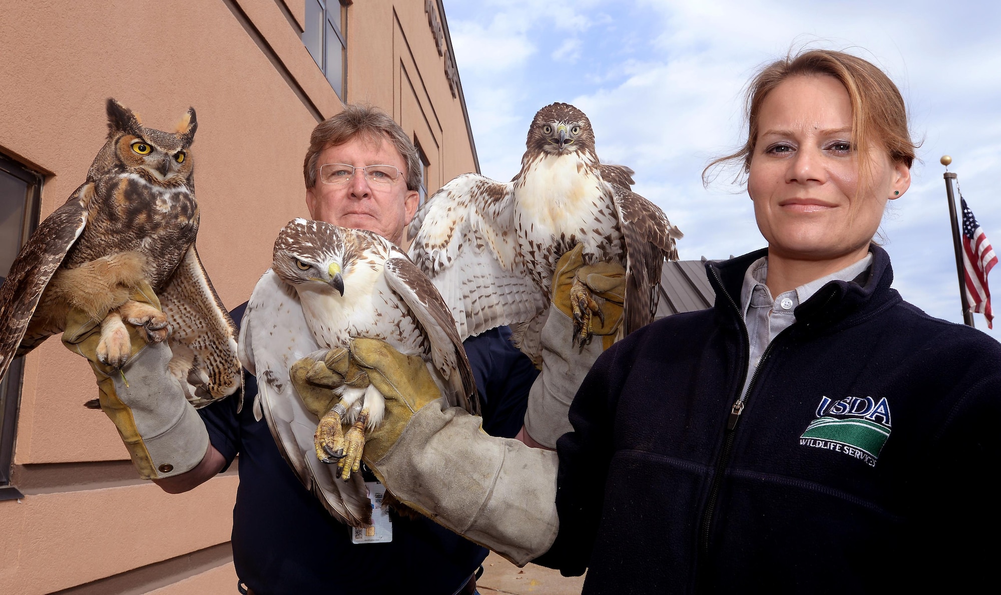 Steve Baumann and Marie Griffin, U.S. Department of Agriculture wildlife biologists, pose for a photo with two red-tailed hawks and a great horned owl Oct. 19, 2016 at Offutt Air Force Base, Neb. The raptors were captured on Offutt’s airfield as part of the Bird/Wildlife Aircraft Strike Hazard program that helps mitigate bird strikes. (U.S. Air Force photo by Delanie Stafford/Released)