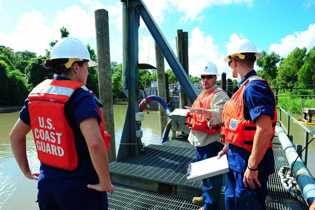 Coast Guard petty officers communicate an environmental health and safety coordinator during a facility inspection. Coast Guard facility inspectors inspect the hoses that transfer oil in order to prevent environmental pollution. (U.S. Coast Guard photo by Petty Officer 3rd Class Carlos Vega)