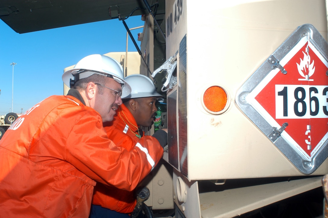 One of hundreds of Army trucks that will be loaded onto the USNS Medonca gets a close look by Coast Guard Petty Officers  after a possible hazardous materials leak is detected during their routine inspection of the many vehicles. (U.S. Coast Guard photo by Petty Officer 2nd Class Danielle DeMarino)