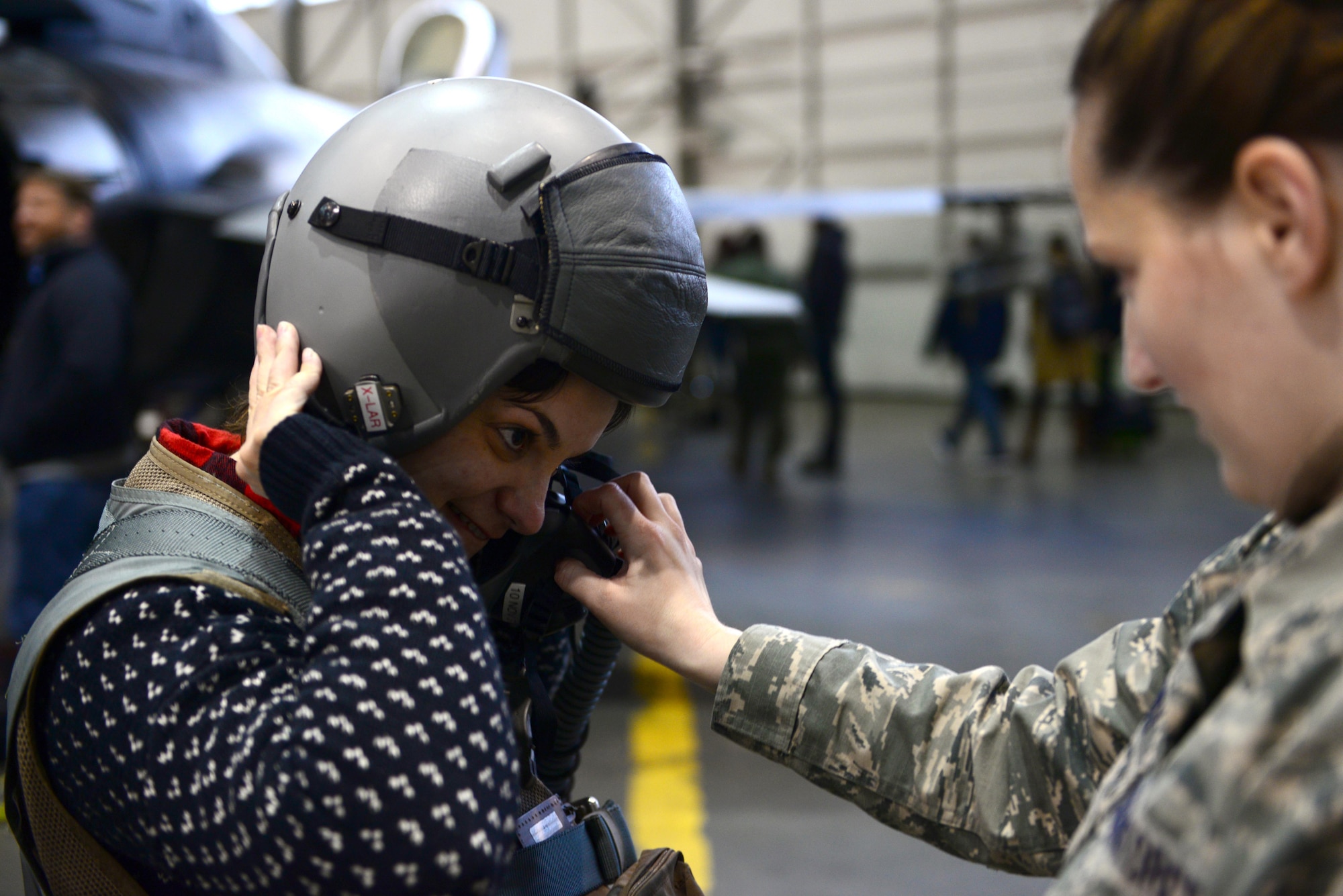 U.S. Air Force Staff Sgt. Skye Perry, a 354th Operations Support Squadron aircrew flight equipment craftsman, helps Kim Barrante, a screenwriter, try on a pilot’s helmet during a Civic Leader Tour, Oct. 25, 2016, at Eielson Air Force Base, Alaska. As part of the tour, civic leaders had the opportunity to meet pilots, observe static displays and try on flight crew equipment. (U.S. Air Force photo by Airman Eric M. Fisher)