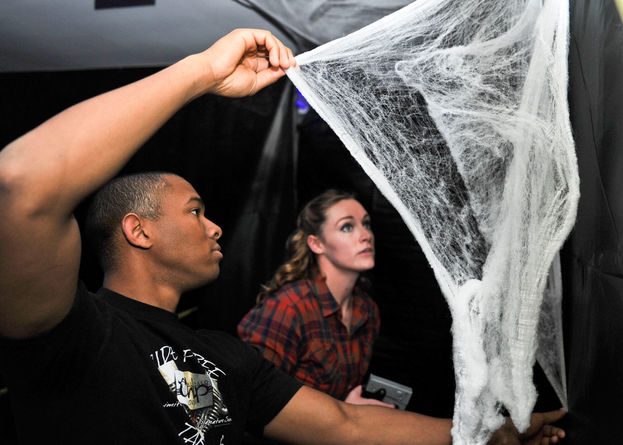 Airman 1st Class Gregory Smith, an avionics technician, and Senior Airman Amber Burns, a non-destructive inspection expert, both assigned to the 28th Maintenance Squadron, hang up decorations for Haunted Camp Lancer on Oct. 27, 2016. Haunted Camp Lancer will be available to all military, dependents and DOD civilians Oct. 28 and 29 from 6-9 p.m. The event is free for all guests, but canned goods or winter clothing donations are encouraged and will be given to the local community. (U.S. Air Force photo by Airman 1st Class Randahl J. Jenson) 