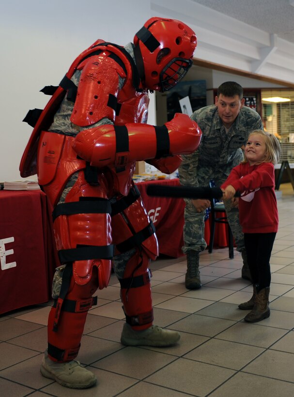 Tech. Sgt. Nathan Patterson, the non-commissioned officer of police services assigned to the 28th Security Forces Squadron, watches as a child demonstrates the proper way to strike an aggressor during a Red Suit demonstration during National Crime Prevention Month at Ellsworth Air Force Base, S.D., Oct. 12, 2016. In addition to the demonstration, the 28th SFS also put together a "superhero day", where volunteers walked around the base neighborhoods dressed as comic book characters and handed out candy to children. (U.S. Air Force photo by Airman 1st Class Denise M. Jenson)