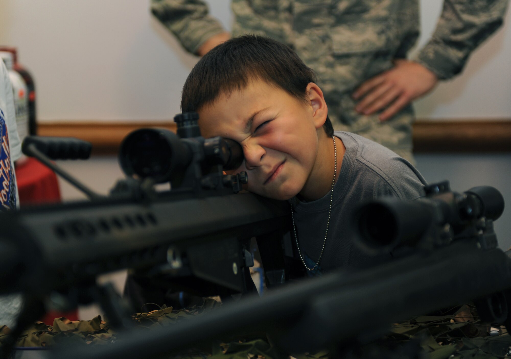 A child looks through the scope of a rifle during a weapons display as part of National Crime Prevention Month at Ellsworth Air Force Base, S.D., Oct .12, 2016. The 28th Security Forces Squadron will be holding a raffle to offer children on base the chance to participate in a "Cop for a Day" event from Nov. 24 to 28, where the winner will get to ride-along with 28th SFS personnel. (U.S. Air Force photo by Airman 1st Class Denise M. Jenson) 