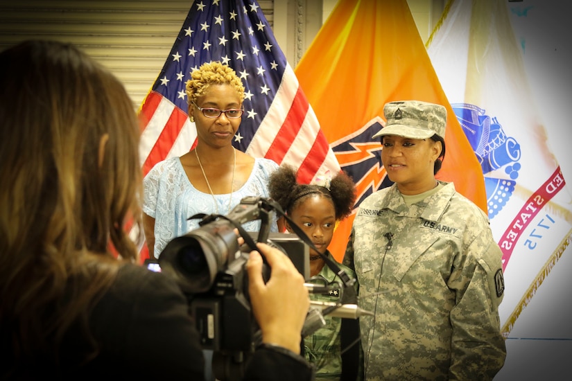 Army Reserve Sgt. 1st Class Katrice S. Osborne (right), a human resources specialist and native of Georgetown, South Carolina, assigned to Detachment 4, 335th Signal Command (Theater) stands with members of her family and answers questions from a local television reporter following a deployment ceremony at the unit headquarters in East Point, Georgia Oct. 30.  Nearly 70 Soldiers from the unit are deploying to Southwest Asia in support of Operation Inherent Resolve.  (Photo by Sgt. 1st Class Brent C. Powell)