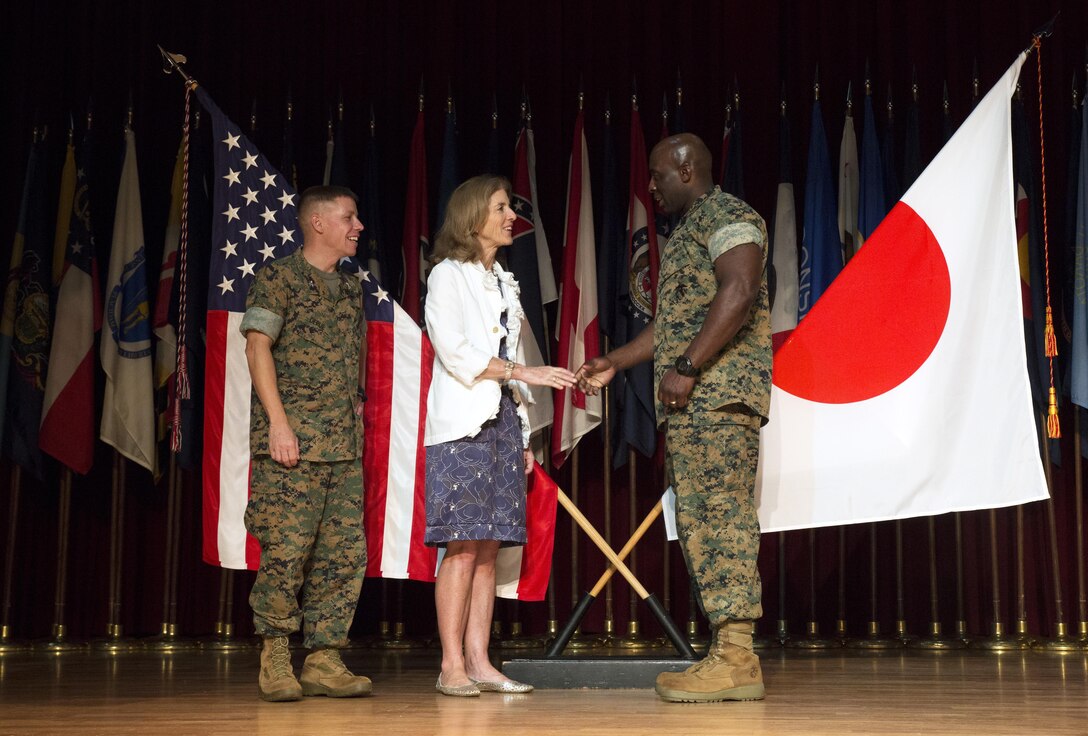 Ambassador Caroline Kennedy, center, greets Sgt. Maj. Jeffrey A. Young, right, and Col. William DePue, left, Oct. 28 aboard Camp Foster, Okinawa, Japan. The community center was one stop along a tour of the military installations across Okinawa during which Kennedy addressed senior military leadership and their families living on Okinawa directly. “I am always inspired by the patriotism I see here when I visit,” said Kennedy. “I want to thank everyone here for everything that you do for this outstanding partnership with Japan. There is a lot to learn here and all you leaders are doing a great job maintaining positive community involvement. I encourage you to continue to educate service members to ensure that we continue to enjoy the support and alliance we have here in Japan.” After her speech, Kennedy posed for photos with attendees and their families. Young is the sergeant major of Headquarters and Support Battalion, Marine Corps Installations Pacific. DePue is the camp commander of Camp Foster and the commanding officer of H&S Bn., MCIPAC.
