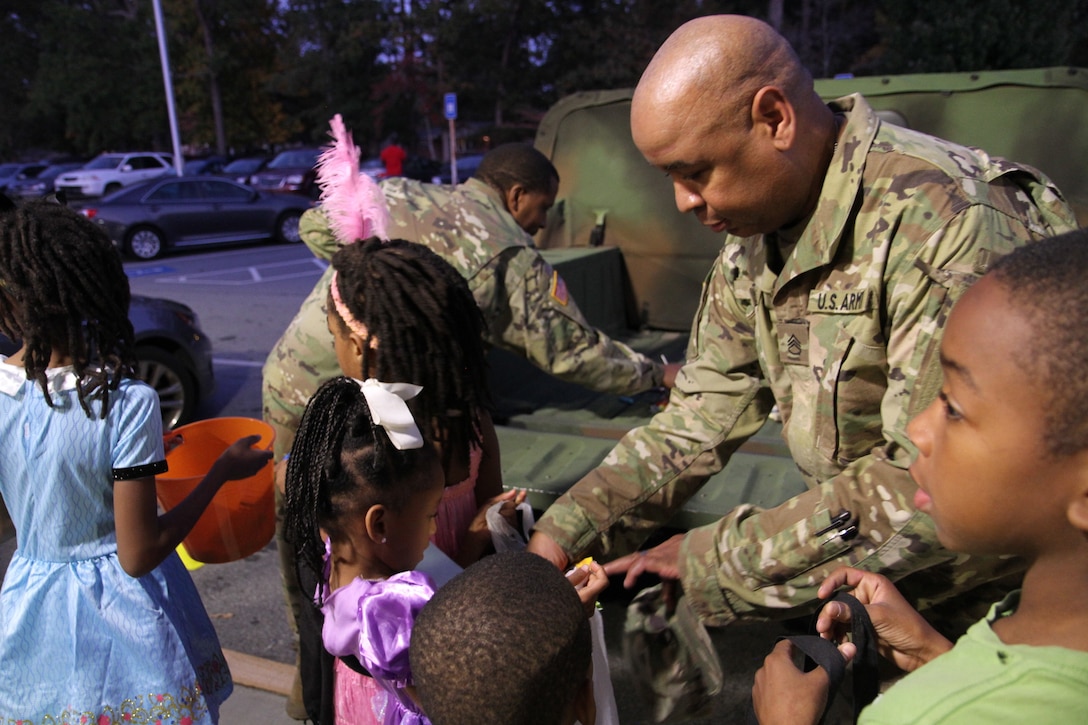 Staff Sgt. Dixon and Sgt. Mugabo hand out Halloween candy to children during the Trunk or Treat event held at Church Street Elementary School.