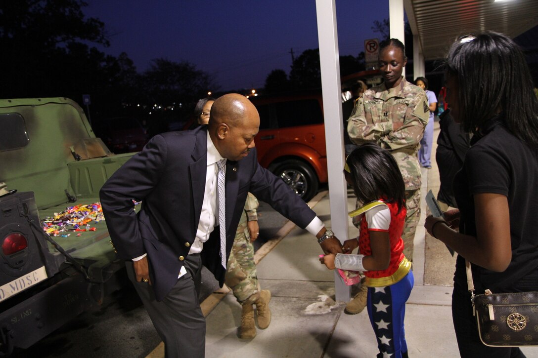 Mr. Patrick Fowler, 3d MCDS Family Programs Coordinator, and Capt. Afua Boahema hand out Halloween candy to children during the Trunk or Treat event held at Church Street Elementary School.
