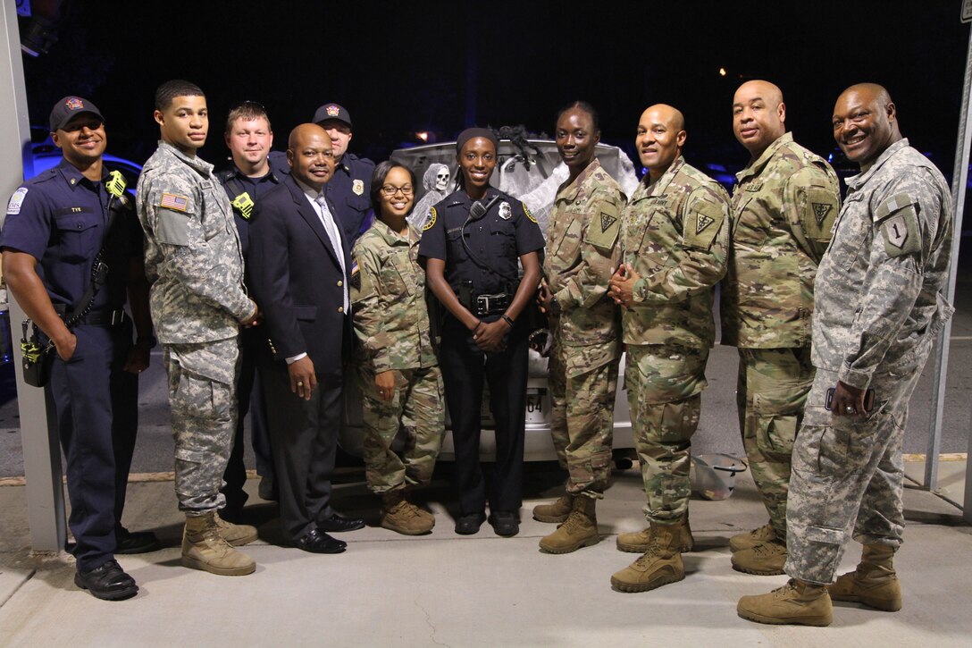 3d MCDS Soldiers, Mr. Patrick Fowler, the Family Programs Coordinator for 3d MCDS, members from the Riverdale Fire Department, and Riverdale Police Department take a group photo after handing out Halloween candy to Church Street Elementary School students during the Trunk or Treat event.